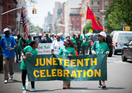 Participants march in the Juneteenth celebration parade through the streets of Harlem in New York